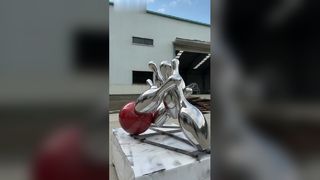 A escultura de boliche espelhada em aço inoxidável captura vividamente o momento dinâmico